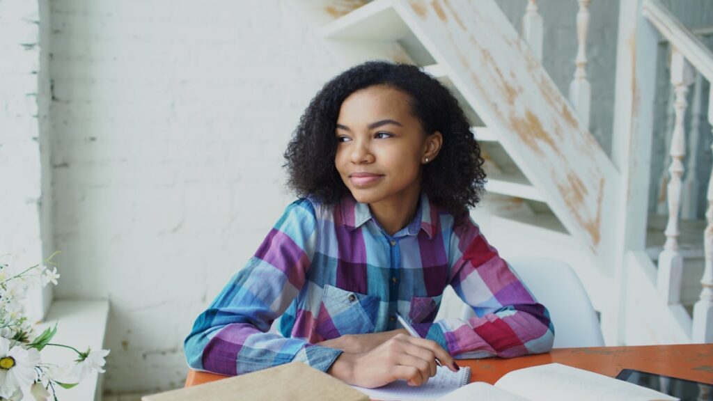 Young woman writing at a desk with books